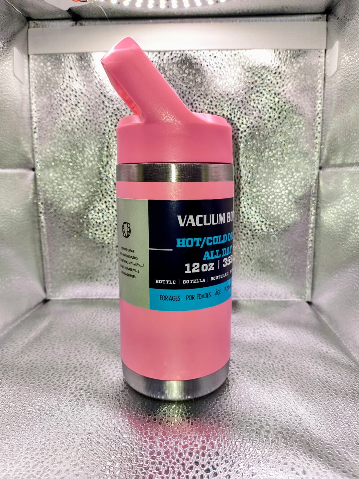 Pink insulated bottle with a label on a reflective surface